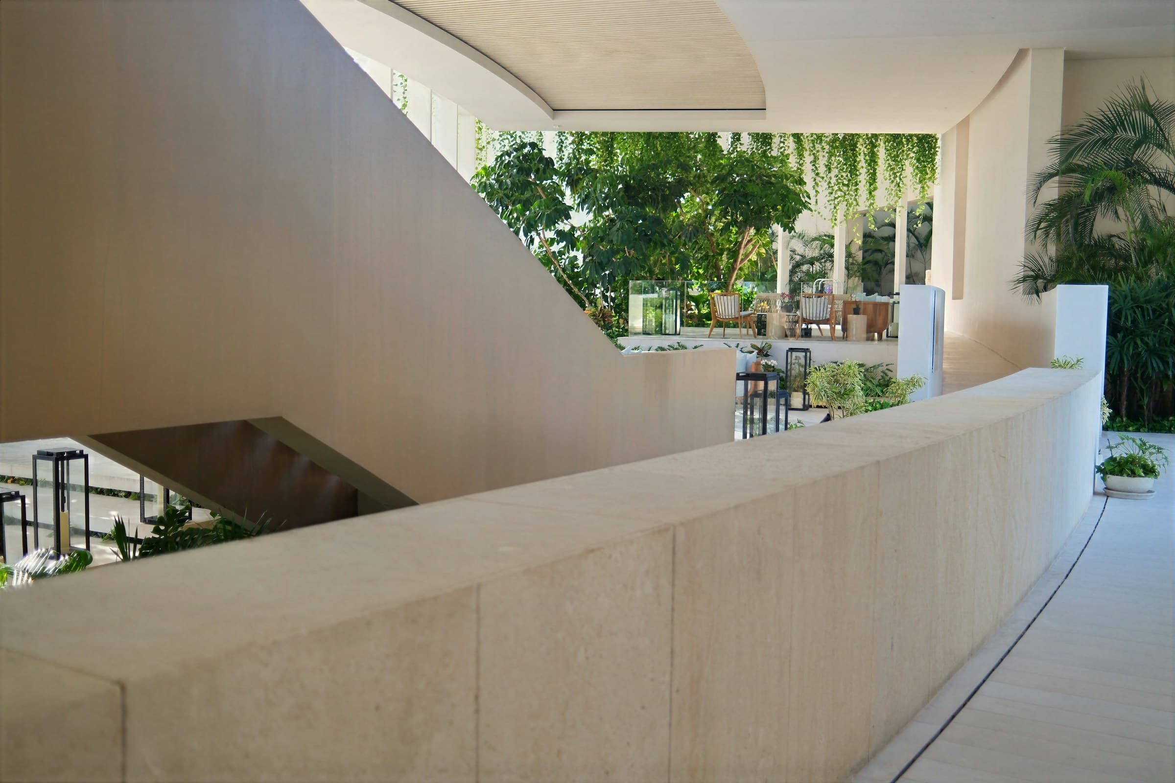 Bright contemporary interior with beige walls, a mezzanine, and tropical plants