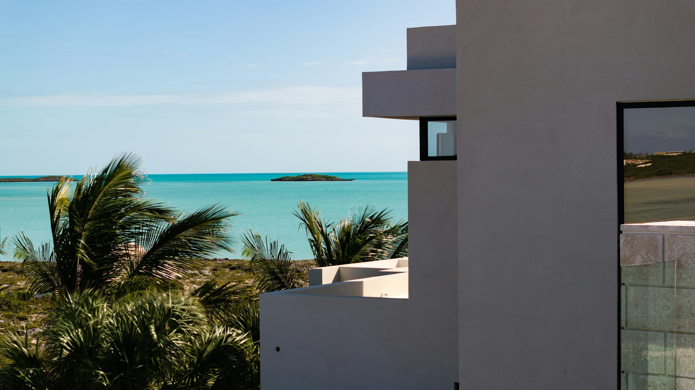 Modern white villa overlooking a turquoise Caribbean sea with palm trees
