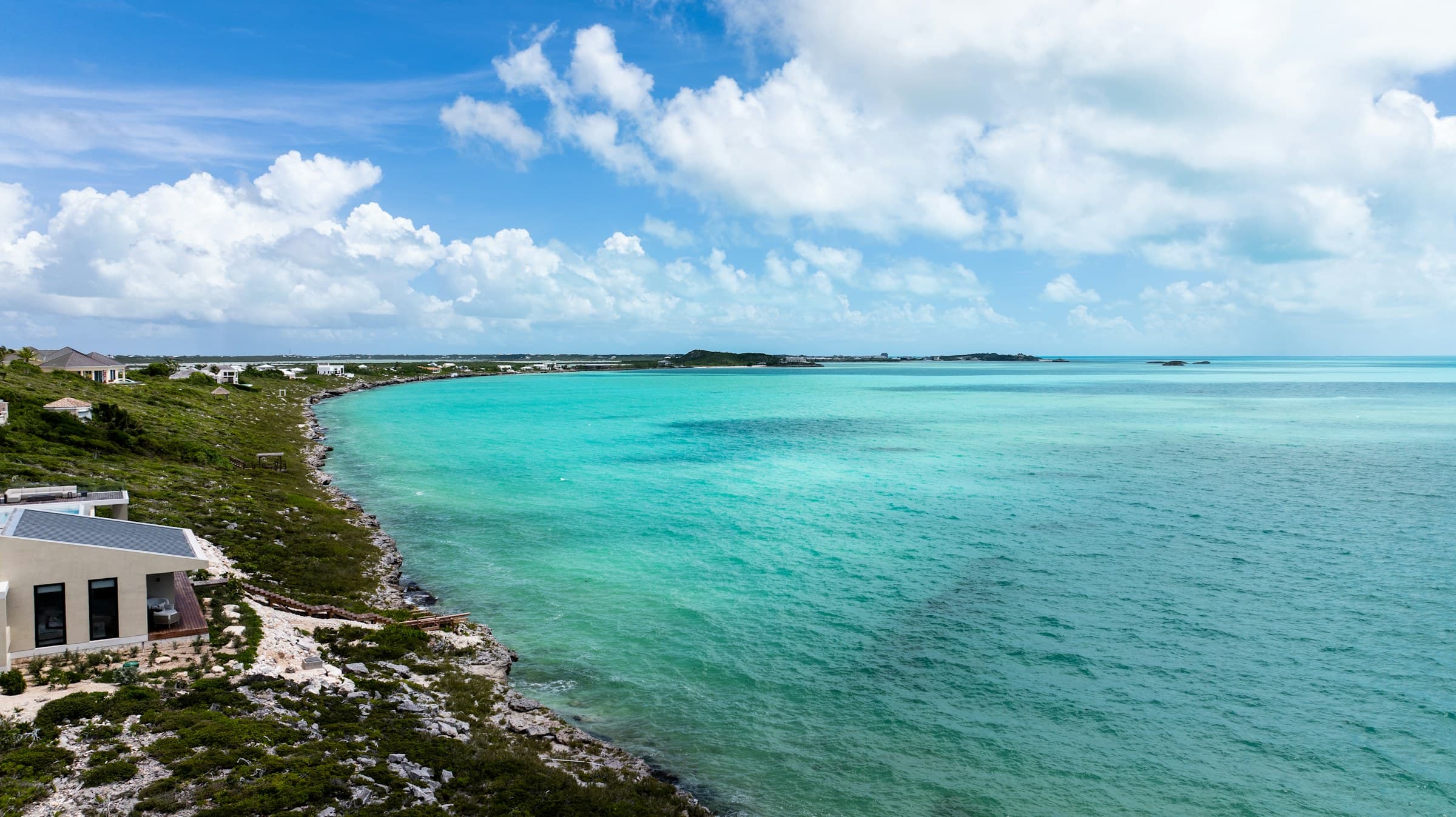 Aerial view of a modern house on a rocky Caribbean coastline above turquoise water